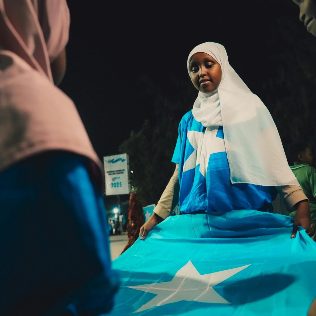 Young person holding the Somalia flag during a night celebration in Mogadishu. Patriotic spirit in Banaadir region.