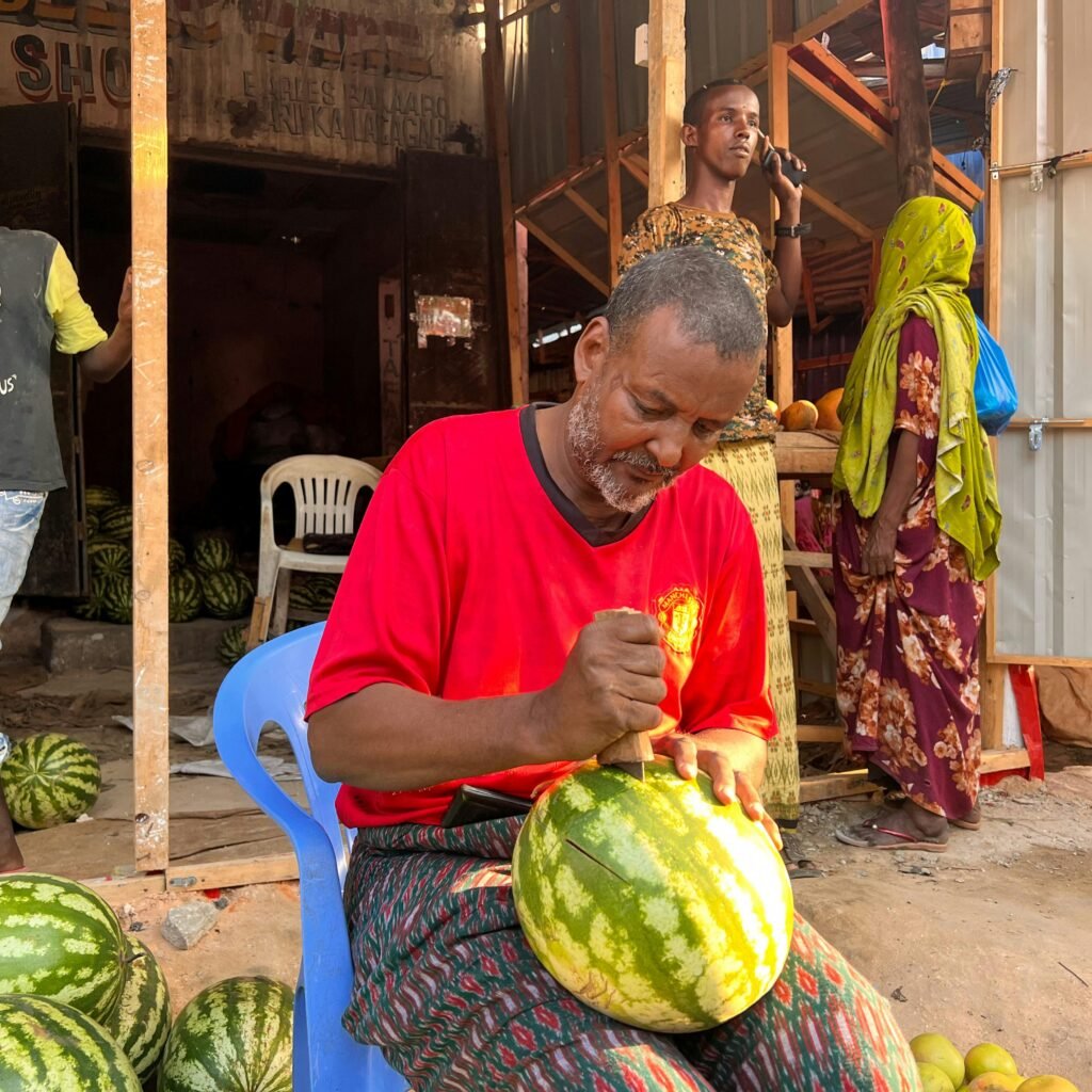 A vendor skillfully slices watermelon at an outdoor market in Mogadishu, Somalia.